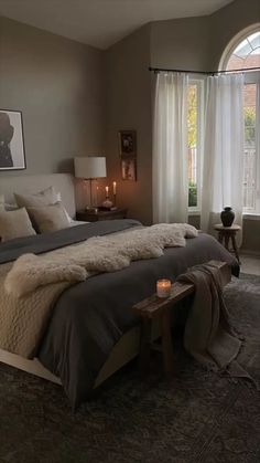 a large bed sitting in a bedroom next to a window filled with curtains and pillows