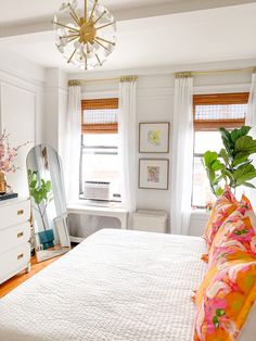 a bedroom with white bedding and colorful pillows on top of the bedspread