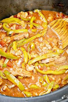 the food is being cooked in the slow cooker with a spatula and wooden spoon