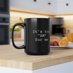 a black coffee mug sitting on top of a kitchen counter next to an orange slice