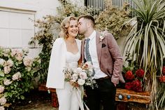 a bride and groom are standing in front of some potted plants with their faces close to each other