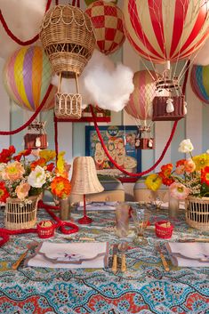 many colorful hot air balloons are in the sky above a table with flowers and other decorations