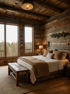 a bedroom with wooden walls and flooring has a large bed in the corner, along with two windows