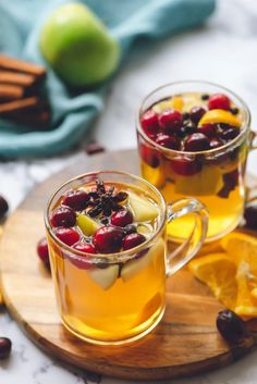 two mugs filled with fruit on top of a cutting board