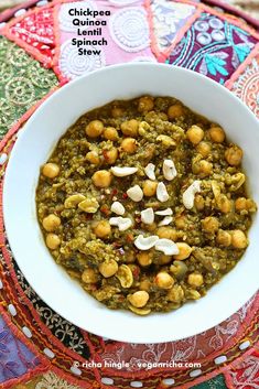 chickpeas and spinach stew in a white bowl on a colorful table cloth