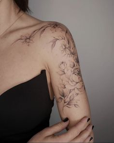 a woman wearing a black dress with flowers on her arm