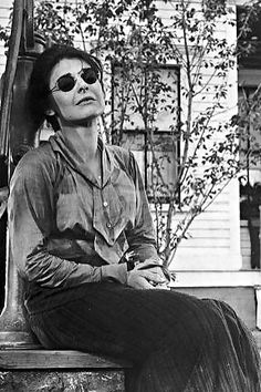 black and white photograph of a woman sitting on a bench with sunglasses on her face