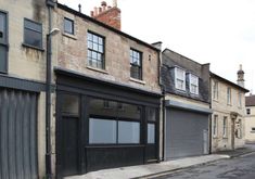 an empty street lined with buildings and garages on either side of the road,