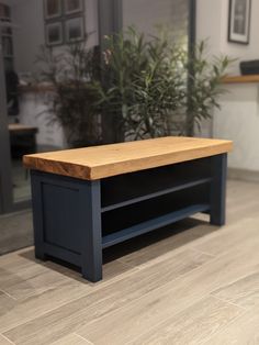 a wooden bench sitting on top of a hard wood floor next to a potted plant