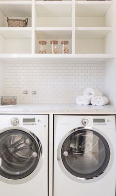 a washer and dryer in a white laundry room with open shelving above