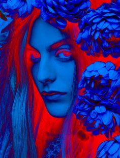 a woman's face is surrounded by blue and red flowers in the foreground