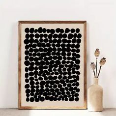 there is a vase with flowers in it next to a black and white art piece