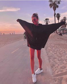 a woman standing on the beach with her arms outstretched