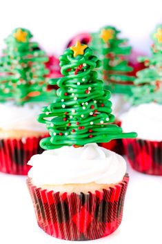 cupcakes decorated with green and red icing are sitting on a white surface