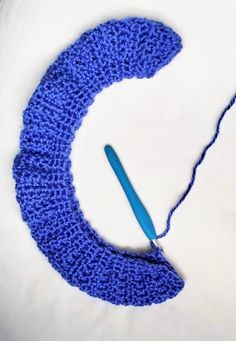 a crocheted object with a blue yarn hook in the shape of a crescent