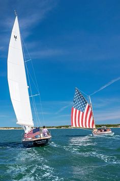 two sailboats in the water with an american flag on them