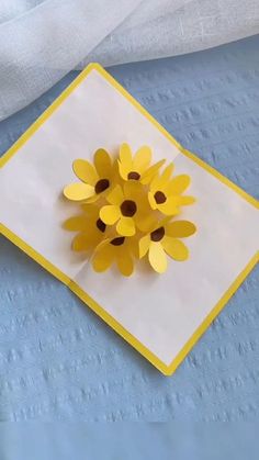 a yellow and white paper flower sitting on top of a blue cloth covered tablecloth