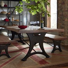 a dining room table with two benches next to it and a wine glass on the table