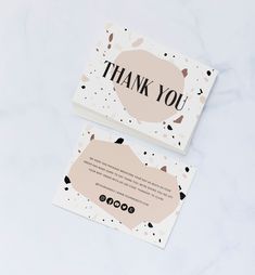 two thank you cards sitting on top of a white table next to an envelope with the words, thank you