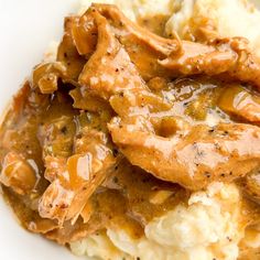 a white plate topped with mashed potatoes covered in gravy