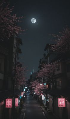 an empty street at night with cherry blossoms on the trees and buildings in the background