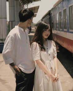 a man and woman standing next to a train