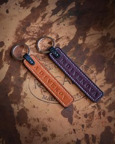 two leather keychains with the word love written on them are sitting on a rusty surface