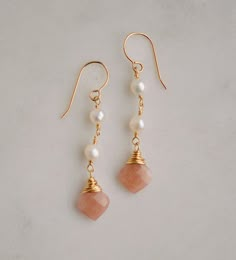 "Genuine Sunstone & Freshwater Pearl Earrings - Sterling Silver or 14k Gold Filled Classic elegance. These lightweight earrings are handmade with white freshwater pearls and natural peach Sunstone.  First discovered in Norway, Sunstone gets its shimmering nature from tiny pieces of Hematite. It is believed that this gem carries the uplifting energy of the sun, and is perfect for those who are stuck in a rut or need a little reminder to live and enjoy life. It is a stone of empowerment that helps Pearl Dangle Earrings, Earrings Inspiration, Freshwater Pearls Earrings, Peach Moonstone, White Freshwater Pearl, Lightweight Earrings, Pearl Earrings Dangle, Matching Necklaces, Classic Elegance