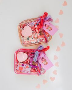 two pink suitcases filled with valentine's treats on top of a white table