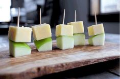 several cubes of food sitting on top of a wooden cutting board with toothpicks sticking out of them