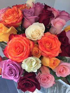 a vase filled with lots of different colored roses