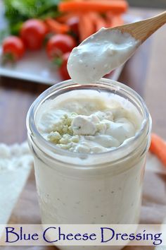 blue cheese dressing in a mason jar with a wooden spoon and carrots behind it