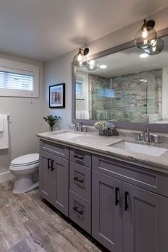 a bathroom with two sinks, a toilet and a large mirror over the vanity area