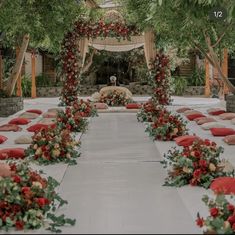 an outdoor wedding setup with red and white flowers on the aisle, surrounded by greenery