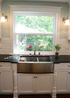 a kitchen with white cabinets, black counter tops and a stainless steel dishwasher