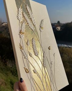 a hand holding up a piece of paper with gold foiling on it and some white flowers