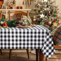 a table with a black and white checkered tablecloth on it in front of a christmas tree