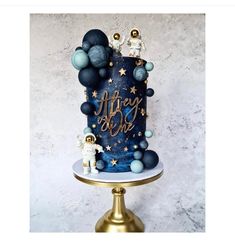 a blue and gold birthday cake with an astronaut on the top, surrounded by stars