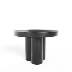 a black round table with three legs on the top and one leg raised to the side