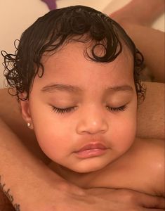 a close up of a baby laying on top of a man's chest with his eyes closed