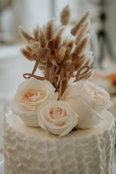 a close up of a cake with flowers and feathers on it's top tier