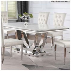 a dining table with white chairs and a silver centerpiece on top of the table