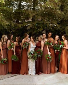 a group of women standing next to each other wearing dresses and holding bouquets in their hands