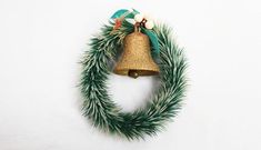 a christmas wreath with a bell hanging from it's side on a white wall