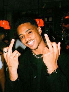 a man making the peace sign with his fingers in front of him at a party