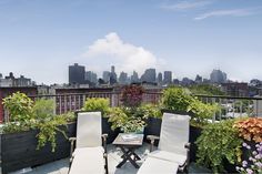 two lawn chairs sitting on top of a roof next to potted plants and flowers