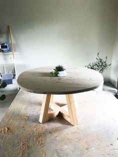 a round table sitting on top of a wooden floor next to a potted plant