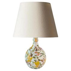 a lamp with a white shade on it and a yellow flowered vase in the center