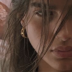 a close up of a person with long hair and earrings on her head, looking at the camera