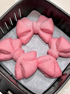 four pink bow shaped cookies sitting on top of a pan